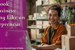 featured image of smiling author at her laptop surrounded by books and shipping boxes for blog post, Your Book as a Business: Thinking Like an Authorpreneur, by Yvonne DiVita